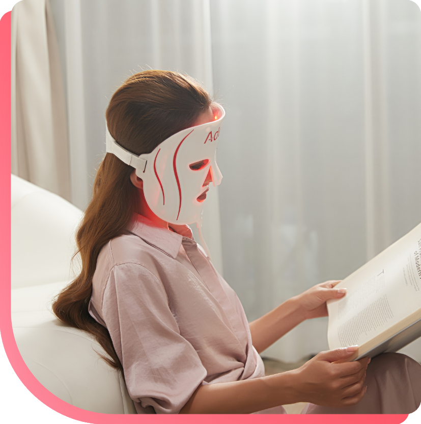 Women wearing light therapy mask reading book